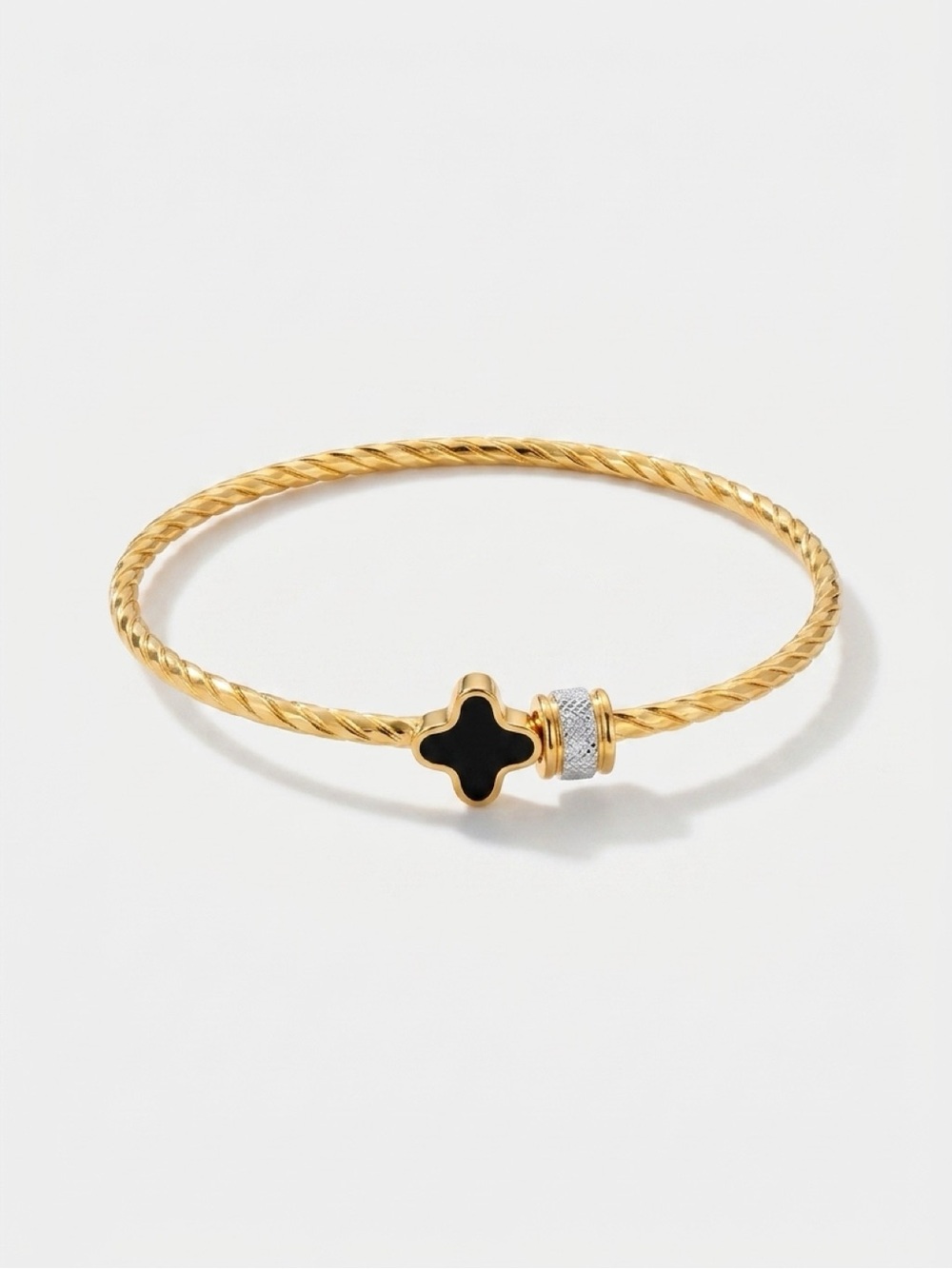 Gold-colored bangle with black quatrefoil and silver charm